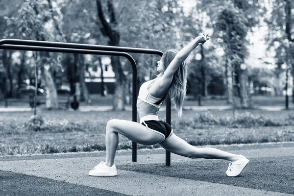 Sportieve vrouw met perfect atletisch lichaam dat zich uitstrekt in het Park. — Stockfoto