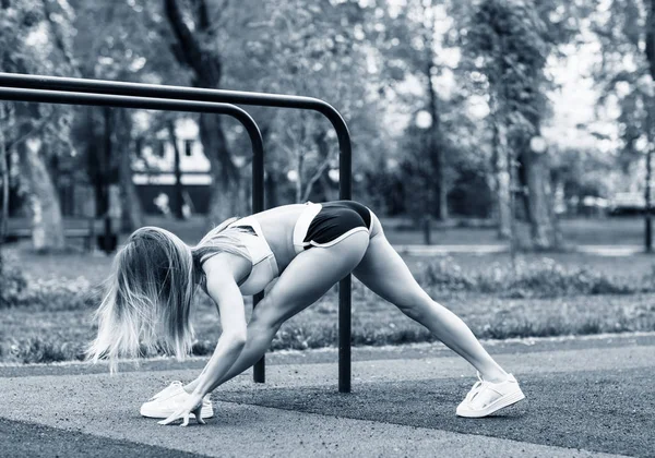 Sportieve vrouw met perfect atletisch lichaam dat zich uitstrekt in het Park. — Stockfoto