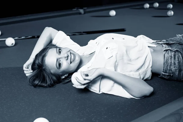 Young woman lying on the billiard table and looking at camera. — Stock Photo, Image