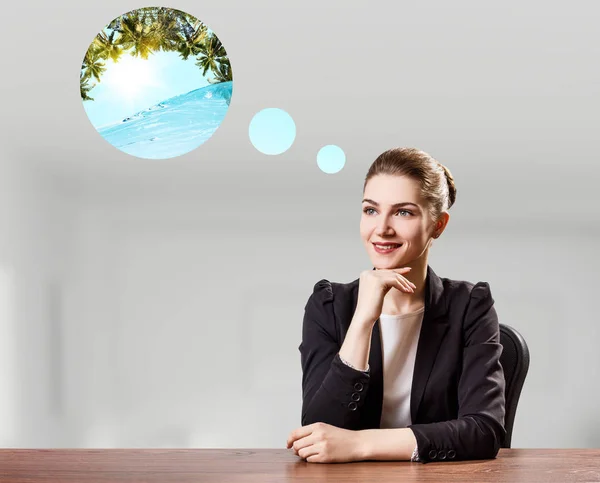 Geschäftsfrau sitzt im Büro und träumt vom Urlaub. — Stockfoto