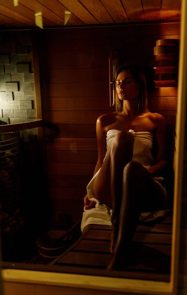 Hermosa mujer envuelta en toalla blanca toma una sauna de madera . —  Fotos de Stock