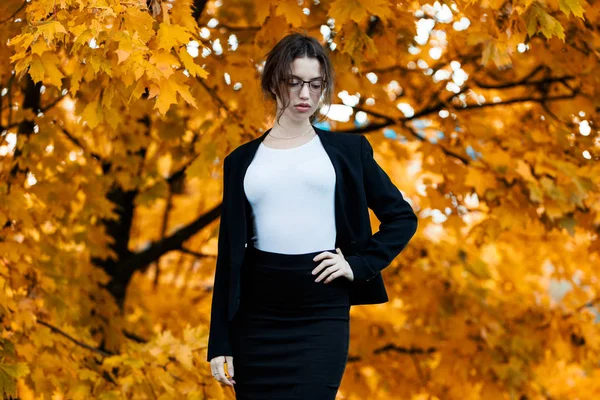 Business woman in formal wear stands over yellow autumn trees. — Stock Photo, Image