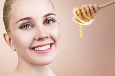 Genç kadın bal ile kaşık bakar ve yüz maskesi için hazırlamak.