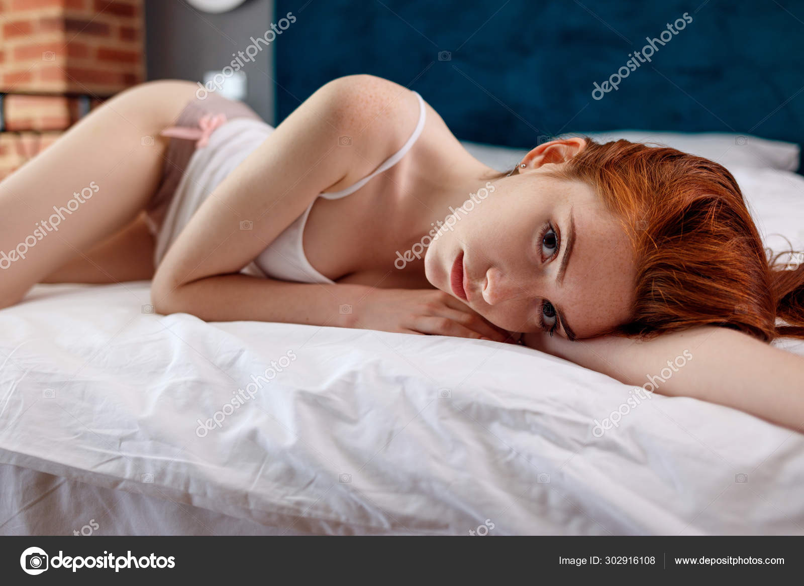 Young redheaded woman half-naked lying on the picture