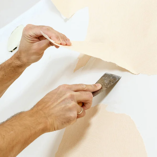 Vista de cerca en las manos con un raspador en el proceso de eliminación de papel pintado . —  Fotos de Stock