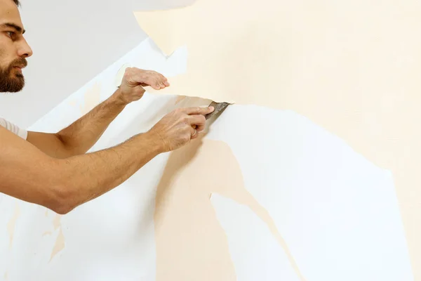 Vista de cerca en las manos con un raspador en el proceso de eliminación de papel pintado . —  Fotos de Stock