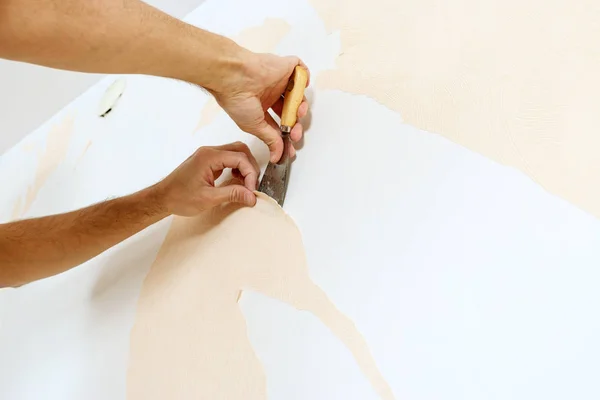 Vista de cerca en las manos con un raspador en el proceso de eliminación de papel pintado . —  Fotos de Stock