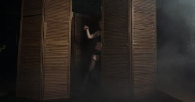 Seksi baskın kadın ahşap panelden görünür.