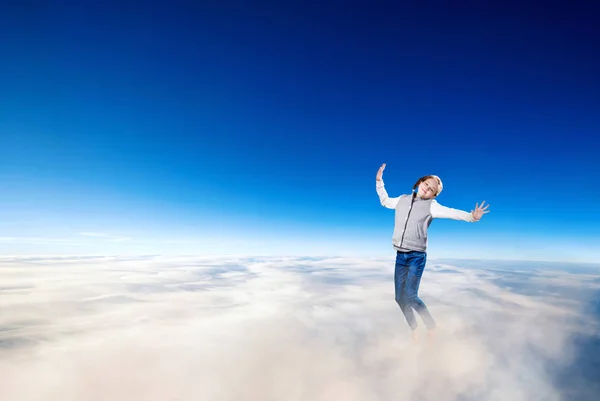Little girl flying over clouds in the blue sky. — Stock Photo, Image