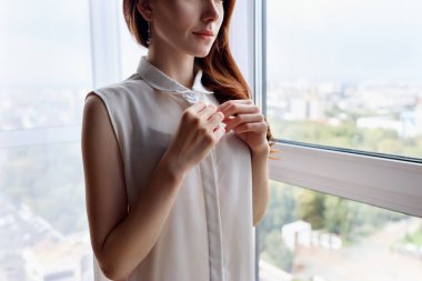 Redhead kadın evde beyaz bluz unbuttoning.