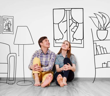 Duvarda boyalı mobilyalar arasında yerde oturan mutlu çift.