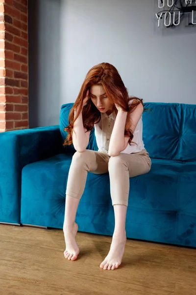 Redhead woman feels bad and suffering from headache at home.