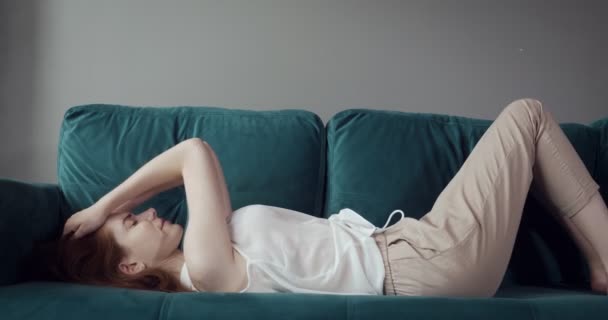 Zrzaná žena, která padá na pohovku doma s bolestí hlavy. — Stock video