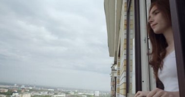 Pencereden şehre bakan genç kadın.