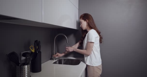 Jeune femme vient à la cuisine pour boire de l'eau . — Video