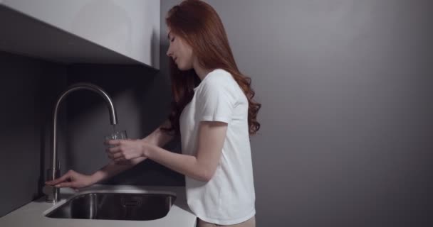 Mujer joven viene a la cocina a beber agua . — Vídeos de Stock