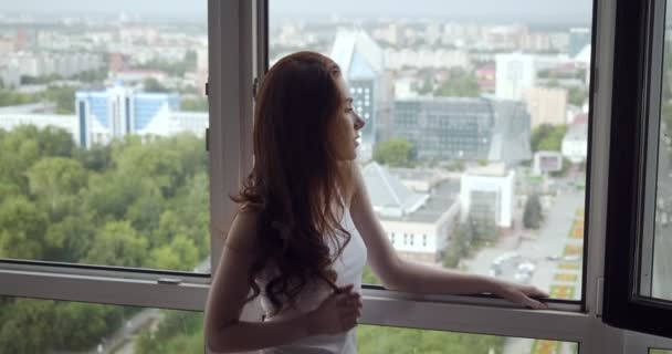 Redhead žena stojí blízko otevřeného okna a v den volna má čerstvý vzduch.. — Stock video