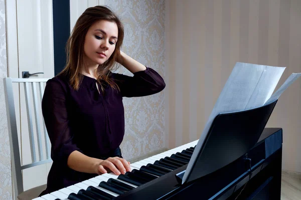 Evde elektronik piyano çalan genç kadın. — Stok fotoğraf