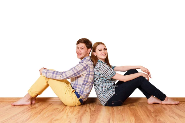 Young happy couple sitting on the parquet floor. — Stock Photo, Image