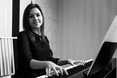 Genç kadın elektronik piyano üzerinde oturan ve oynuyor