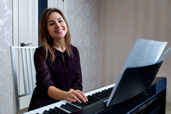 Young woman sitting and playing on the electronic piano — Stock Photo, Image