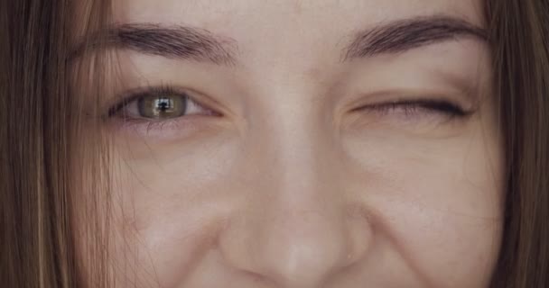 Close-up view on womans eyes looks and winks on camera. — Stock Video