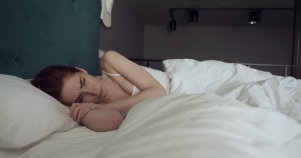 居心地の良いベッドで気分なしで目覚める美しい赤毛の女性. — ストック動画