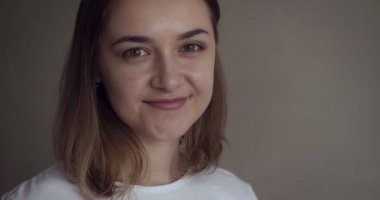 Genç kadın gülümseyip beyaz gülüyor kamera karşılar.