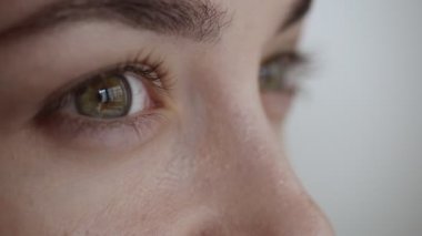 Kadın göz kırpıyor ve uzağa bakıyor.