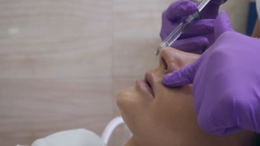 Mor eldivenli doktor kadın dudaklarında iğne yapıyor..