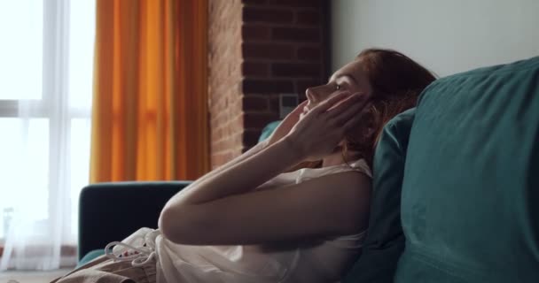 Redhead vermoeide vrouw vallen op de Bank thuis met een hoofdpijn. — Stockvideo