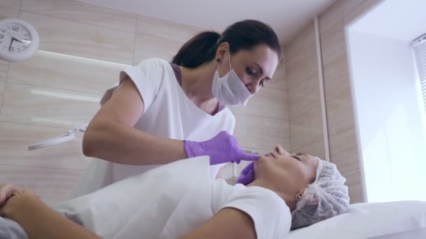 Médico en guantes morados hacer la inyección en los labios de las mujeres . — Vídeo de stock