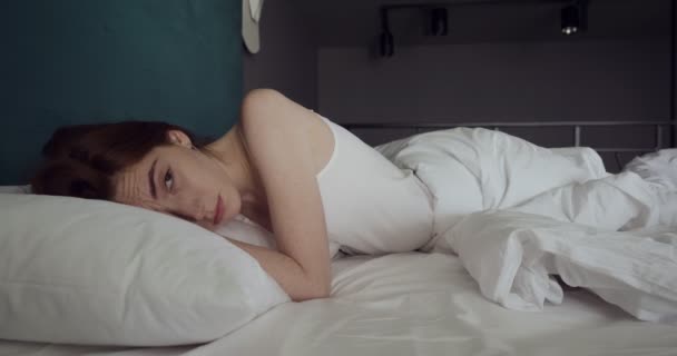 Jonge vrouw ontwaakt in comfortabel gezellig bed. — Stockvideo