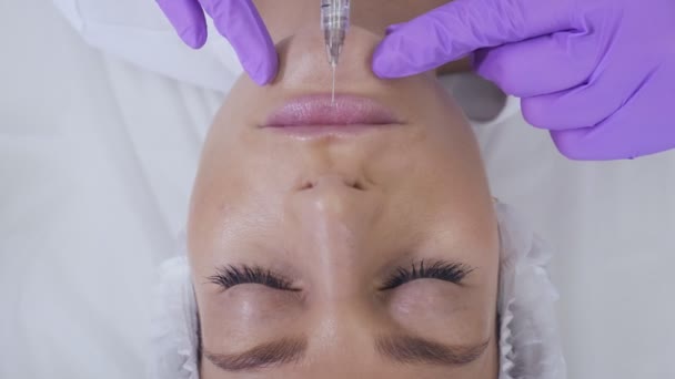 Läkare i lila handskar gör injektion i kvinnors läppar. — Stockvideo