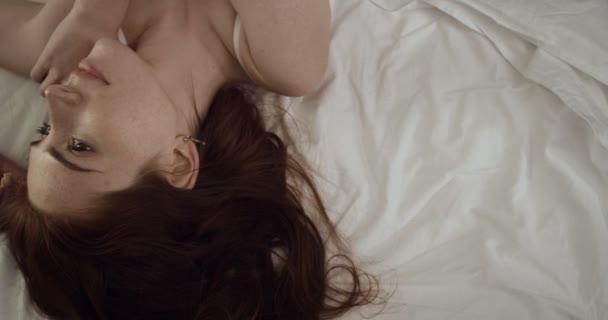 Vista superior de la hermosa mujer posando en la cámara en la cama . — Vídeo de stock
