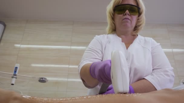 Женщина лежит на столе и получает процедуры лазерной эпиляции . — стоковое видео