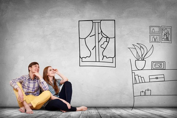 Lyckligt par sitter på golvet bland målade möbler på väggen. — Stockfoto