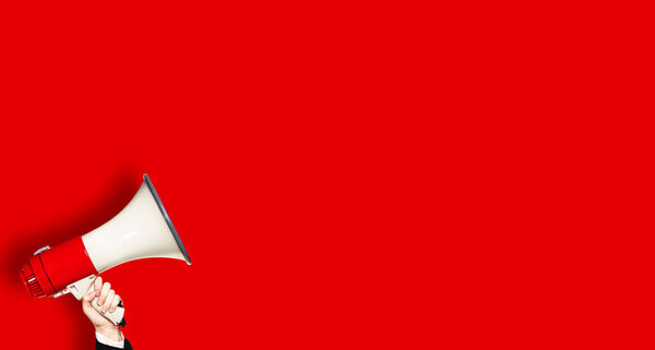 Мегафон в руке над красным фоном
.