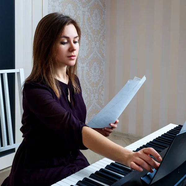 Giovane donna seduta e suonare il pianoforte elettronico — Foto Stock