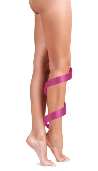 Frauenbeine mit rosa Schleife. Rehabilitationskonzept. — Stockfoto