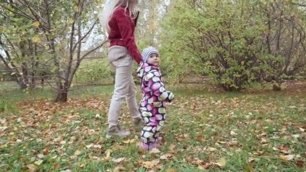Jeune mère et sa petite fille marchent dans le parc d'automne .
