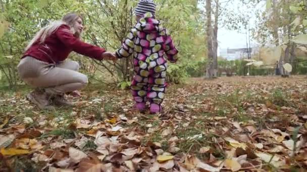 Junge Mutter und ihre kleine Tochter spazieren im Herbstpark. — Stockvideo