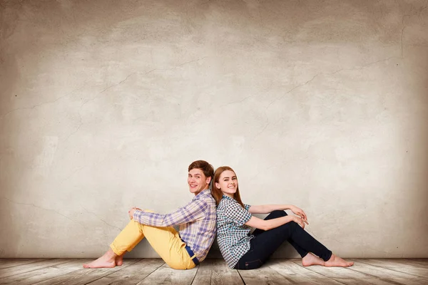 Young happy couple sitting on the parquet floor. — Stock Photo, Image