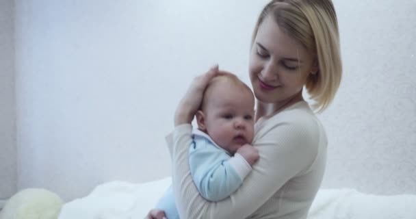 Feliz madre sostiene a su bebé, abrazándose y besándose . — Vídeos de Stock