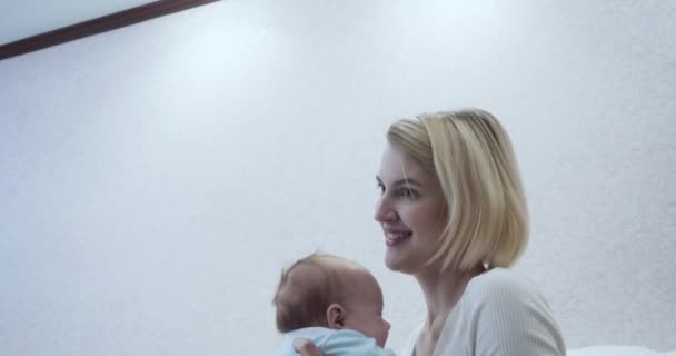 Η μητέρα χαϊδεύει προσεκτικά το μωρό της στην αγκαλιά της στο δωμάτιο.. — Αρχείο Βίντεο