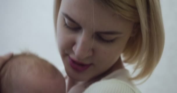 Η νεαρή μητέρα κρατά και αγκαλιάζει το μωρό της που κλαίει με τα χέρια στο σπίτι. — Αρχείο Βίντεο