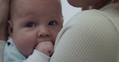 Anne, evdeki oturma odasında bebeğini kucağına alır ve kucağına alır..