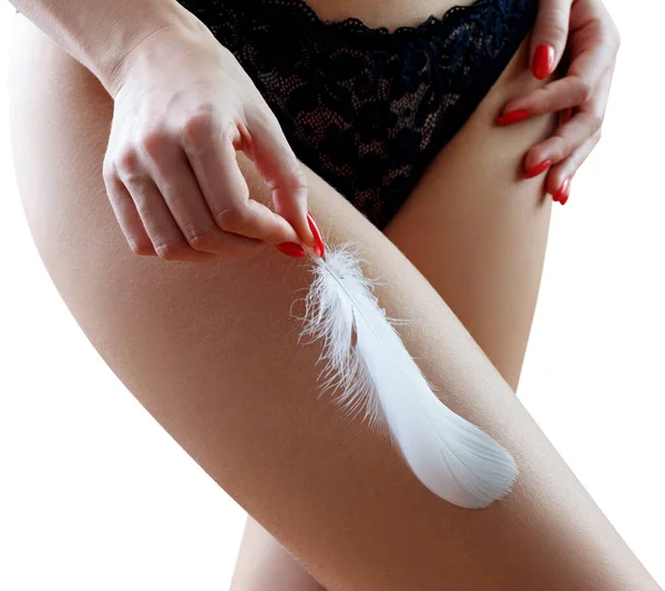 Woman holds the feather over hips background. — Stock Photo, Image