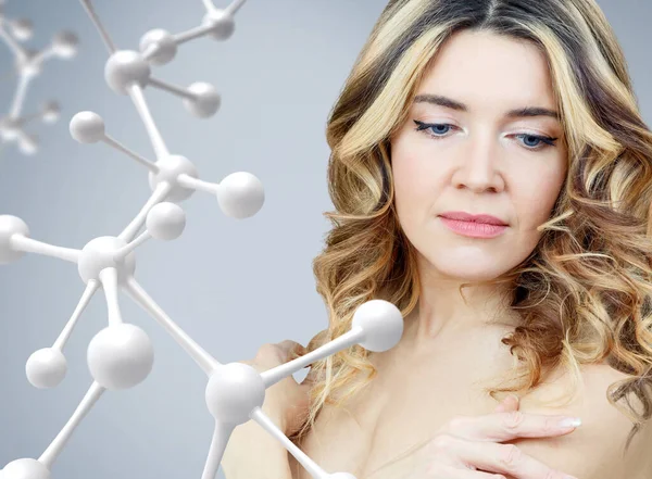 Hermosa mujer adulta cerca de una gran cadena de moléculas blancas . — Foto de Stock