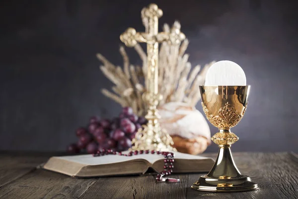 First holy communion theme. The Cross, Holy Bible, rosary and golden chalice. Bread and grapes  symbols of Christianity.